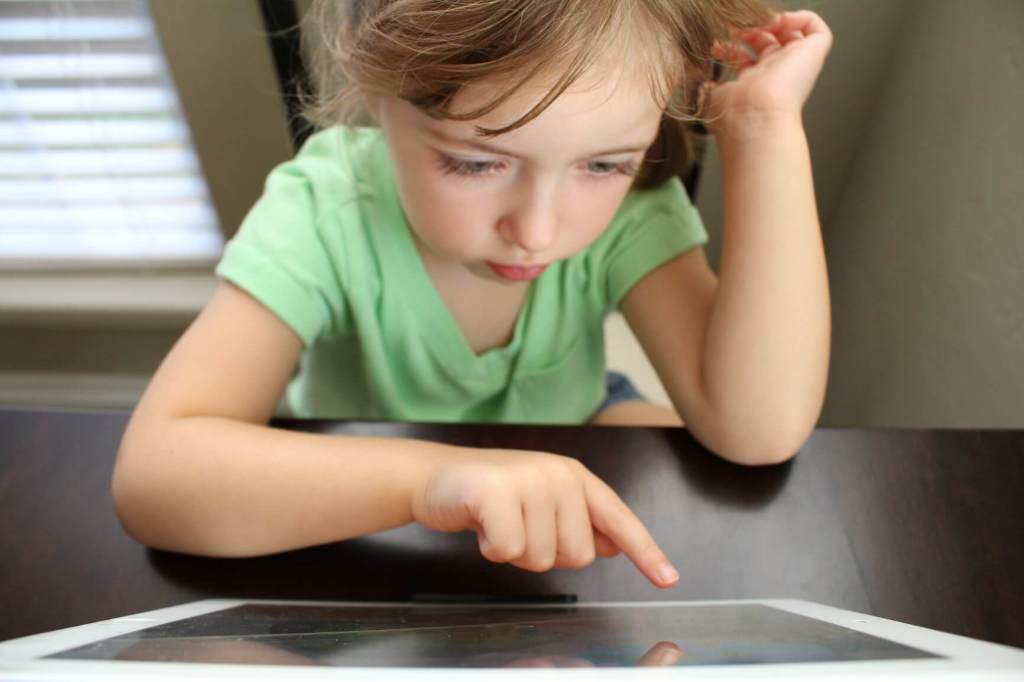 Girl looking at computer. Parents should seek training for helping their kids with autism.