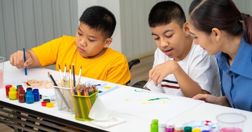 Two Hispanic boys working with teacher on painting project. Is my autistic child eligible for Social Security income?