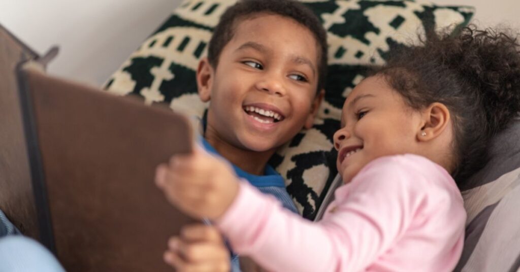 Boy and girl lying in bed and reading a book.