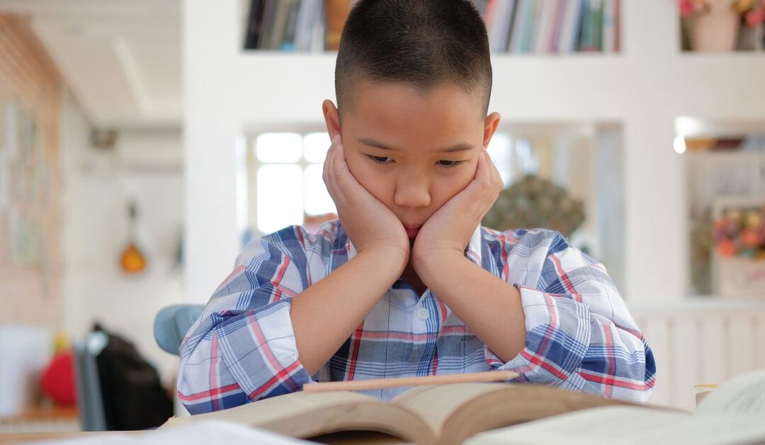 Boy looking at his book bored