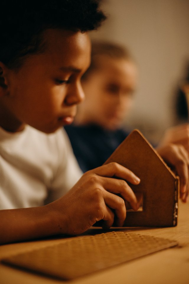 Boy making a gingerbread house. Prepare your autistic child for the holidays.