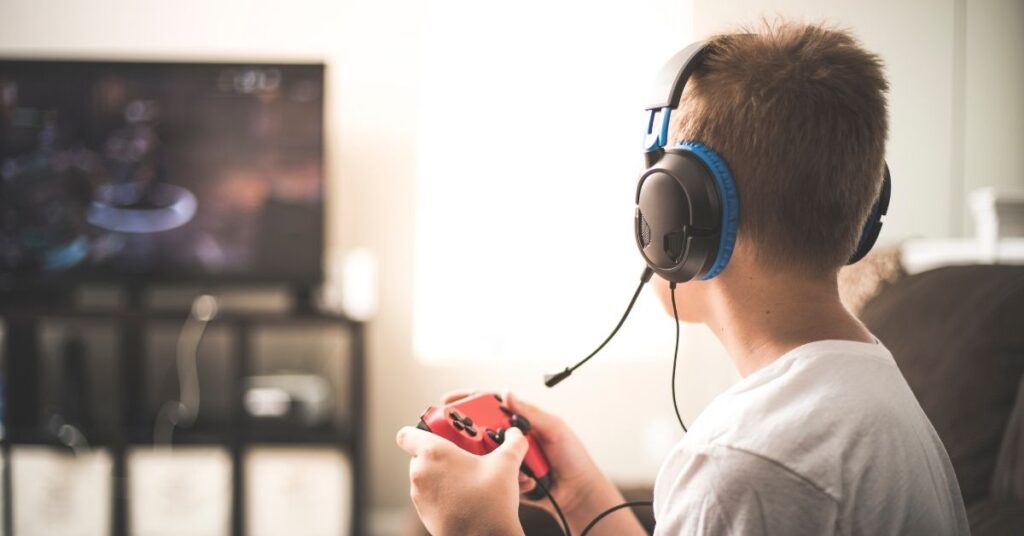 Boy playing video game. What are the pros and cons of screen time for your child with autism and ADHD?