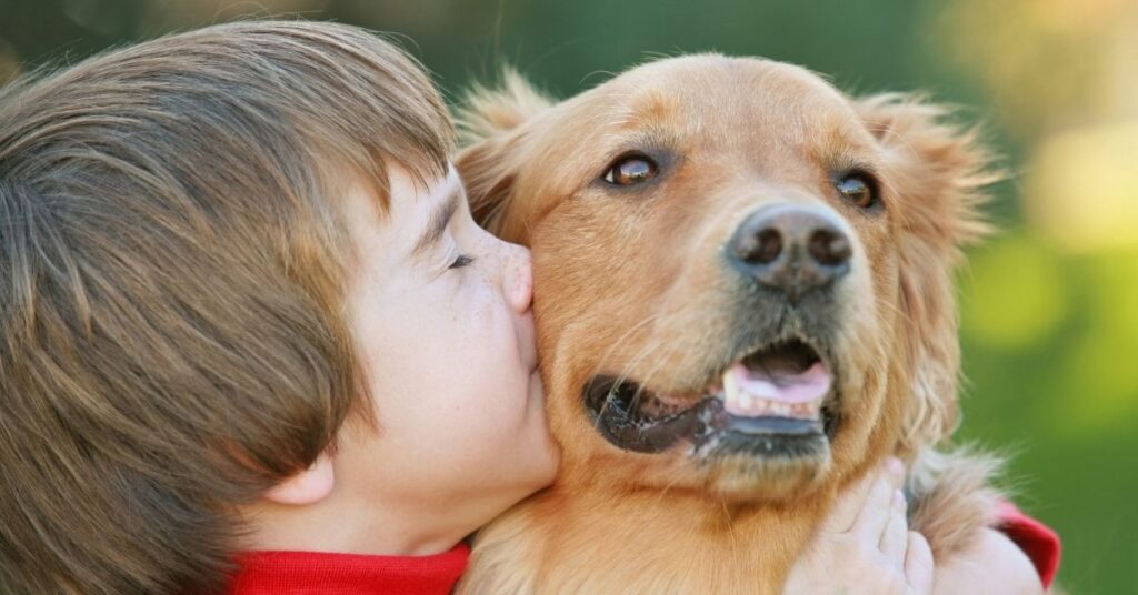 Boy kissing his dog. What is the best dog for a child with autism?