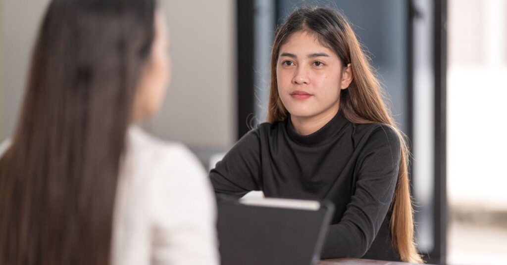 Teen or young adult woman talking to another woman. How can you support your autistic teen or young adult to obtain college accommodations?