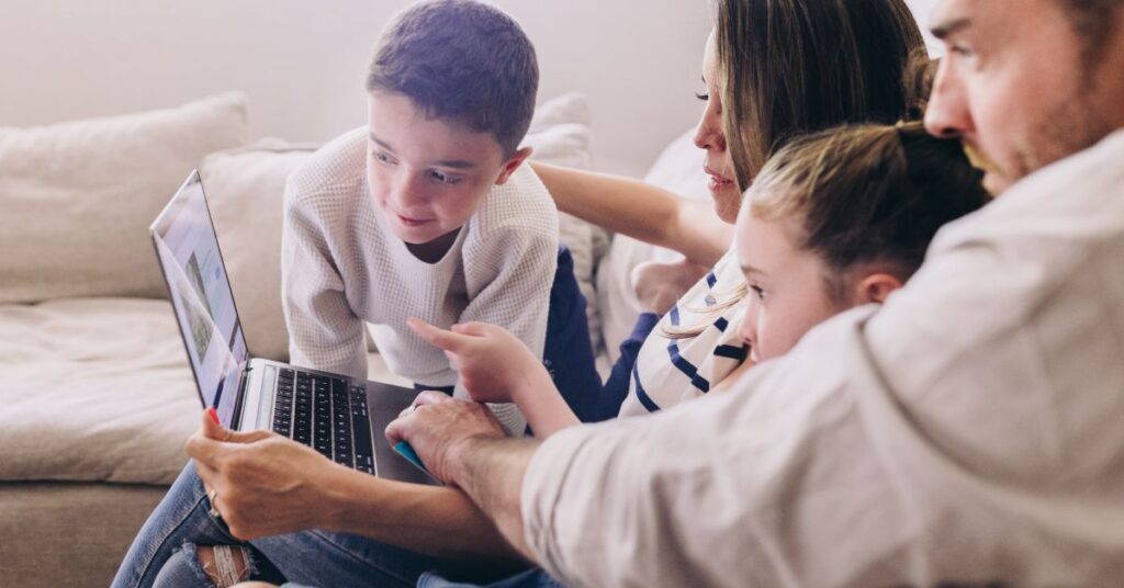 Family sitting at computer planning. How to include goals and actions for your autistic child in your new year planning.