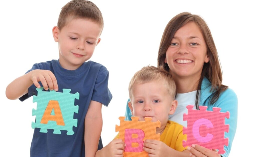 A mom and her two boys hold ABC puzzle pieces