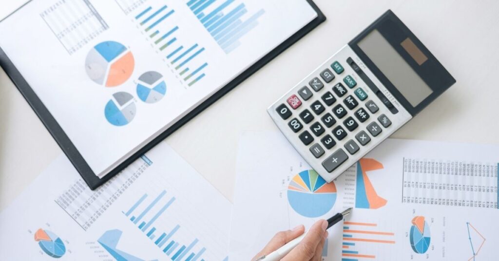 Graphs on paper with calculator and hand holding pen on top of them. What is an ABLE account and can you establish one for your autistic child?