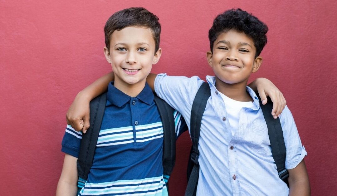 Two boys standing with their arms around each other. Help your autistic child make friends.