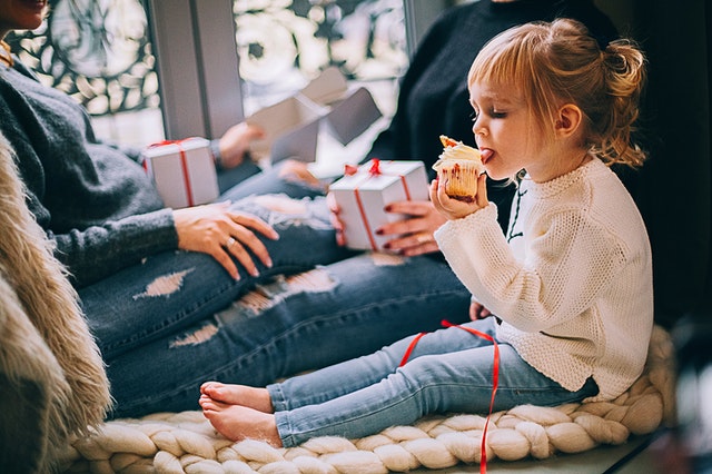 Little girl eating cupcake. Prepare your autistic child for the holidays.