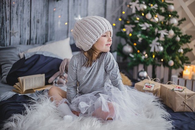 Girl sitting in front of Christmas tree. Prepare your autistic child for the holidays.