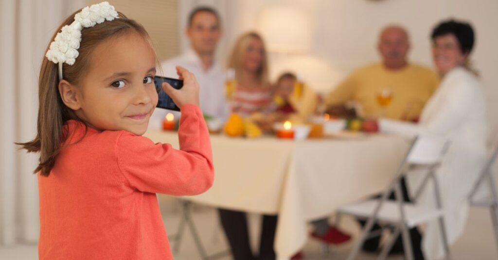 Little girl taking photo of family at their table. Reasons to be thankful for autism.