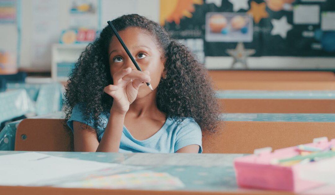 Little girl sitting in class staring at her pencil