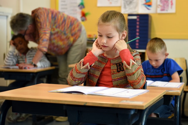 Girl sitting in classroom. How can you help your ADHD child combat forgetfulness?