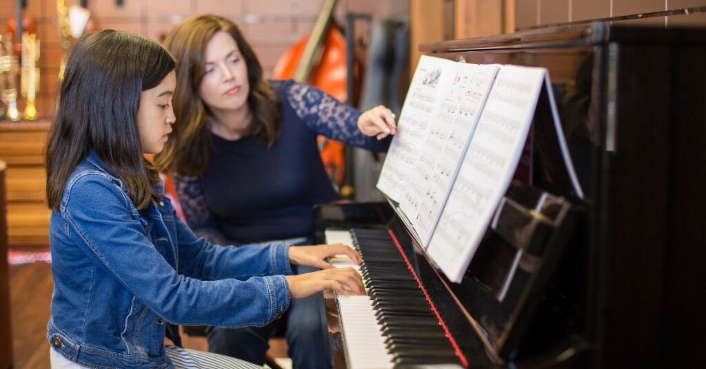 Girl taking a piano lesson. Should you encourage your autistic child to play a musical instrument?