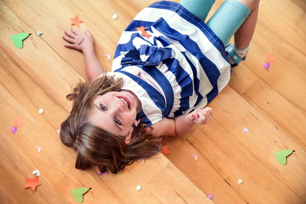 Girl lying on floor with confetti celebrating a victory.