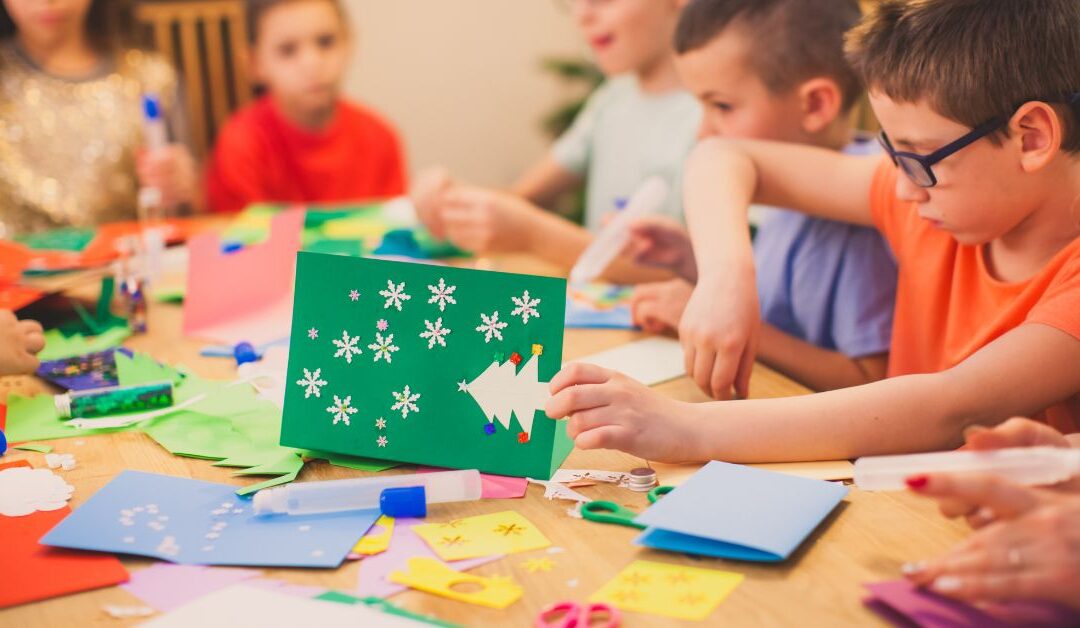 Children sitting at a table making holiday crafts.