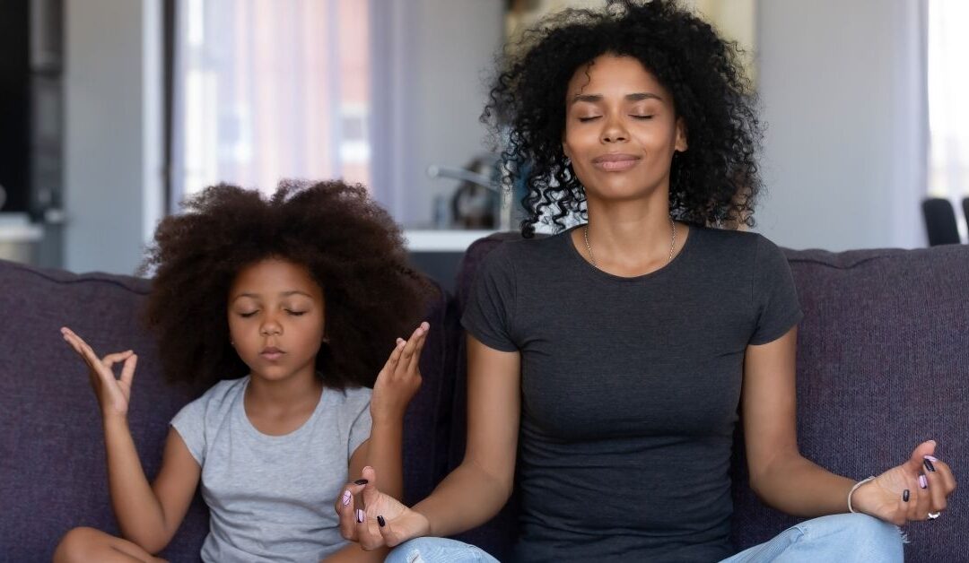 Mom and daughter sitting on couch in meditation pose.