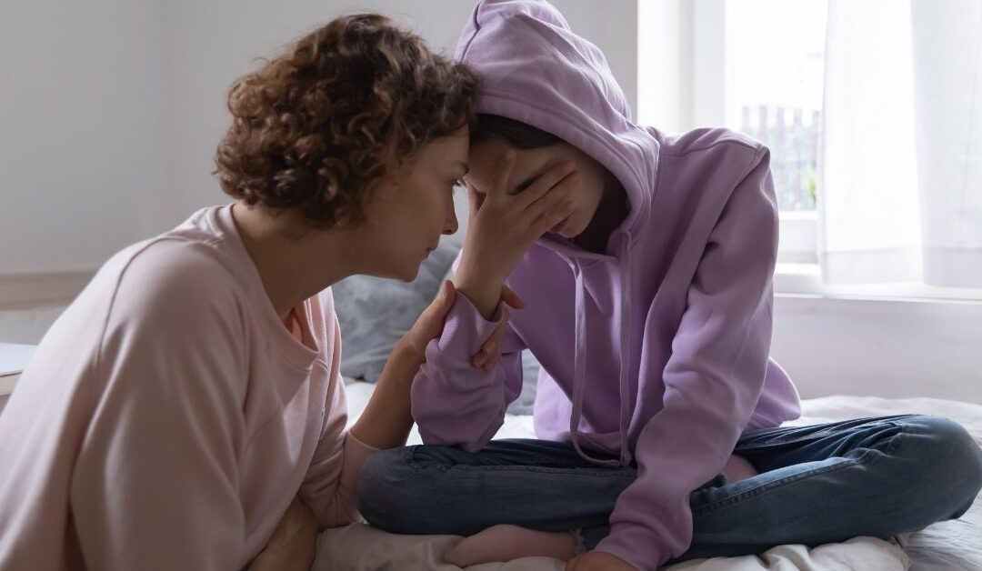 Mom sitting with teen girl who is in distress