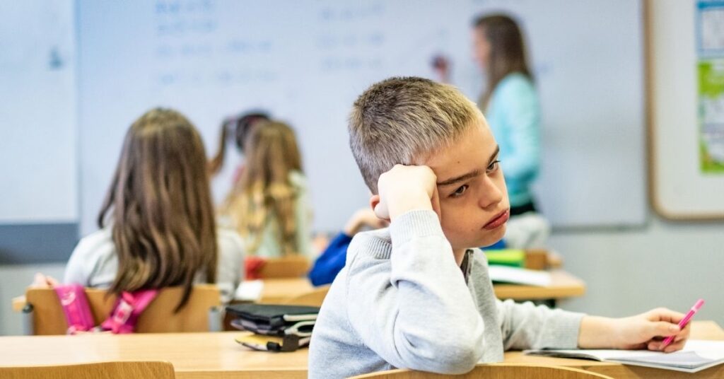 Boy sitting in classroom with head on his hand looking bored. What is pathological demand avoidance?