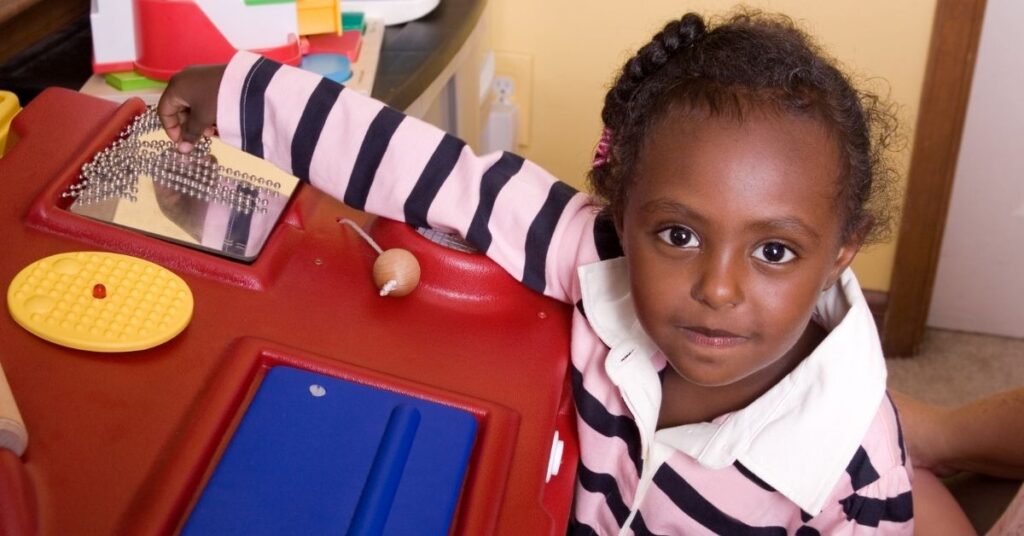 Little girl sitting at a sensory table. Sensory play benefits children with autism and ADHD.