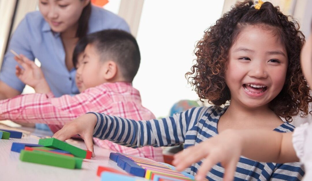 Girl smiling and playing with blocks.