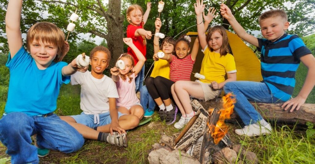 Kids roasting marshmallows at a campfire. Summer camp can benefit children with autism.