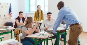 Teacher talking to students in class. How to help your teen with autism and ADHD take more effective notes in class.