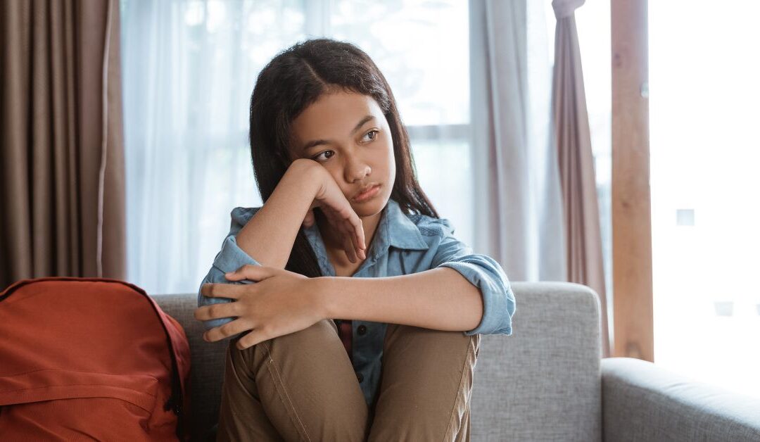 Teen girl sitting on couch feeling emotional. Does your teen with ADHD struggle with rejection sensitive dysphoria?