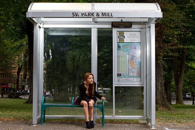 Teen girl sitting at a bus stop. How to build independence in your teenager with autism and ADHD.