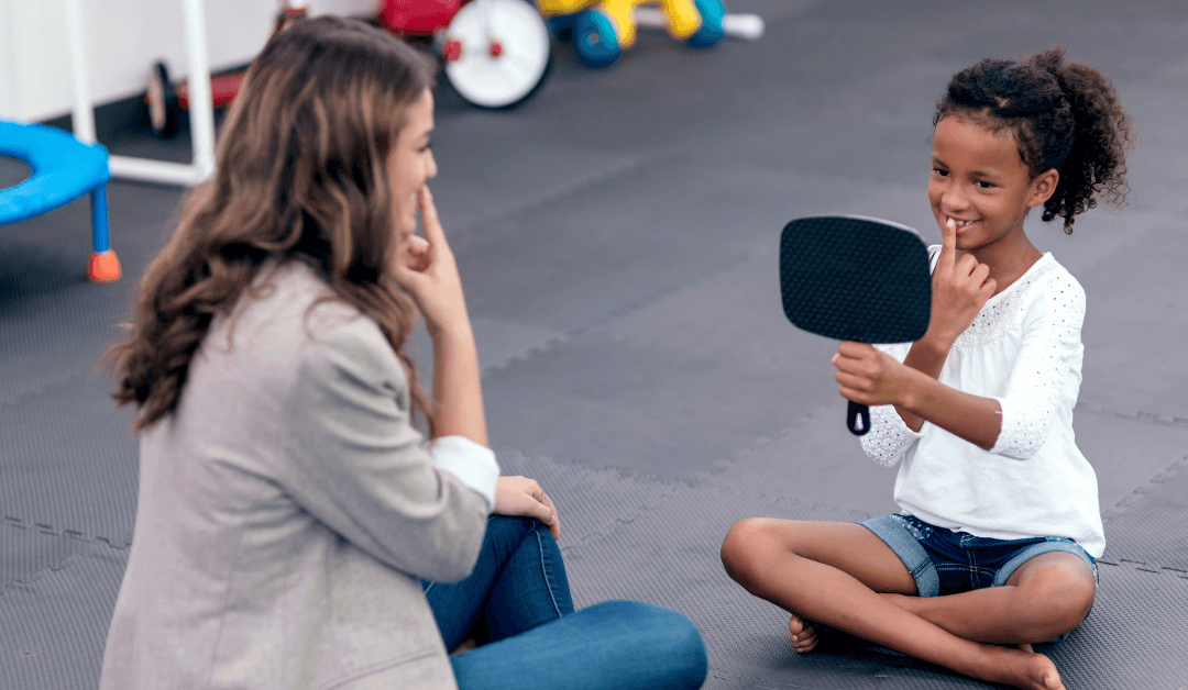 Girl looking in mirror and working with a speech therapist.